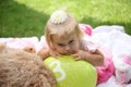 Sweet smiling little girl with long blond hair, sitting on grass in summer park, closeup outdoor portrait. Royalty Free Stock Photo